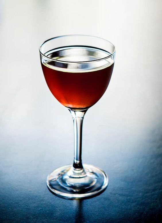 cocktail de aguardente de medronho com ginginha de obidos e chocolate. fundo claro e copo alto com liquido em tons rosé escuro