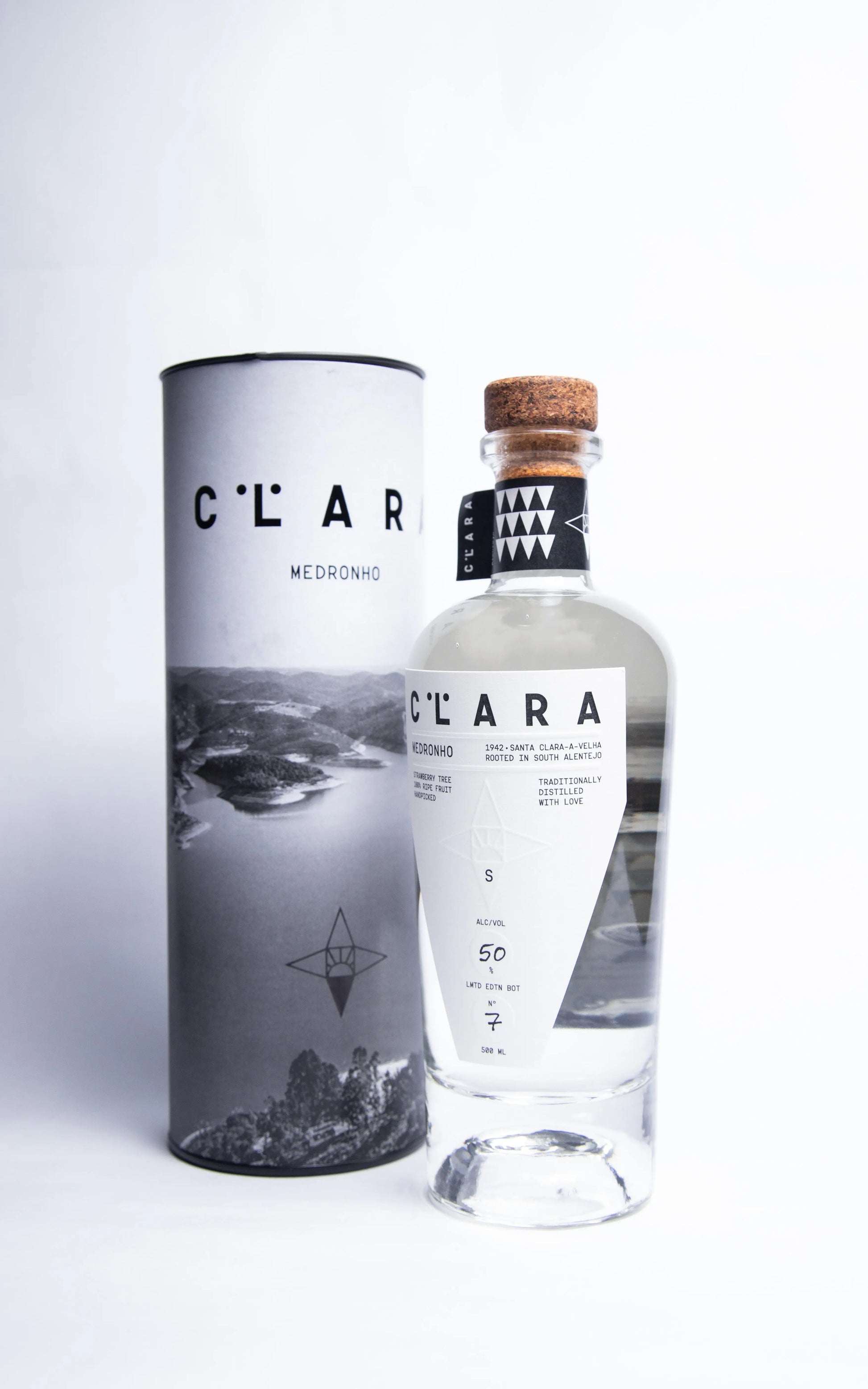 garrafa de Aguardente de Medronho CLARA 500ml em foto de estudio com tubo de cartao de oferta