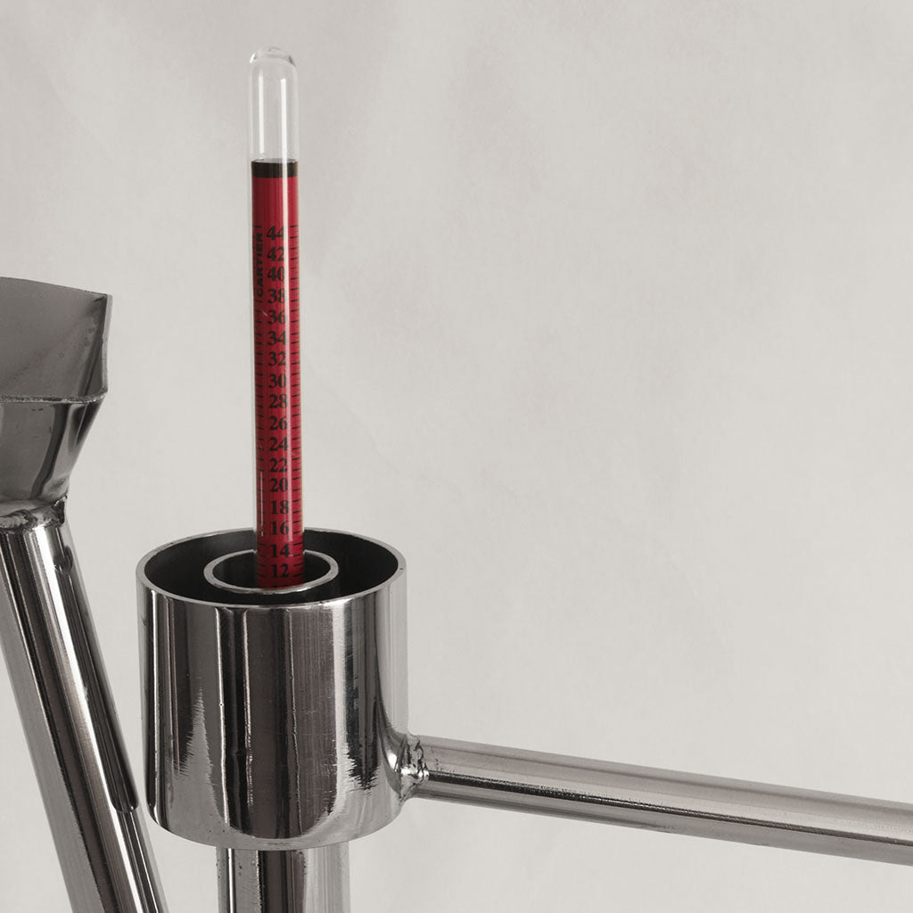 alcoômetro em recipiente de inox para avaliar o volume alcoólico de uma bebida destilada. Especialistas e consultores para fazer aguardente de medronho de elevada qualidade